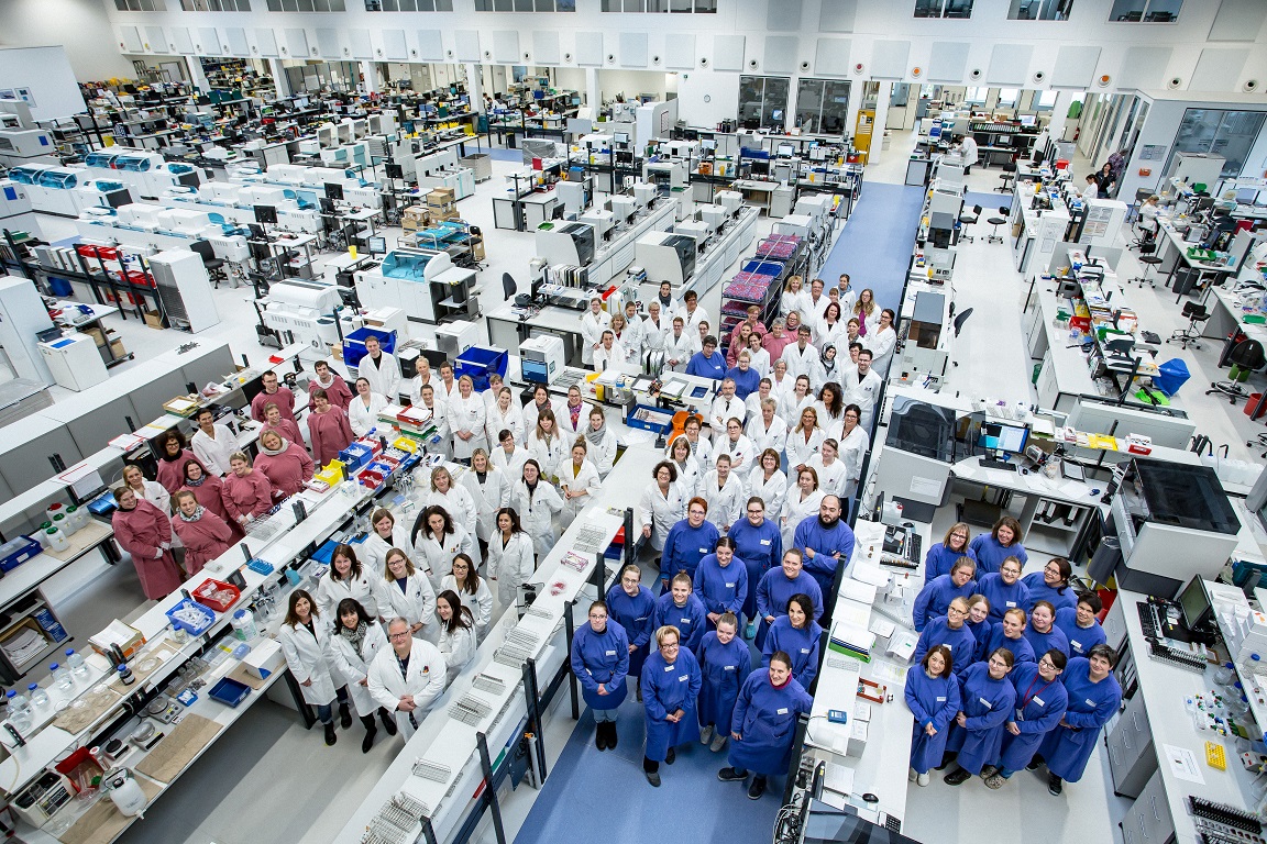 Ein Gruppenbild vom Laborpersonal in einer großen Laborhalle.